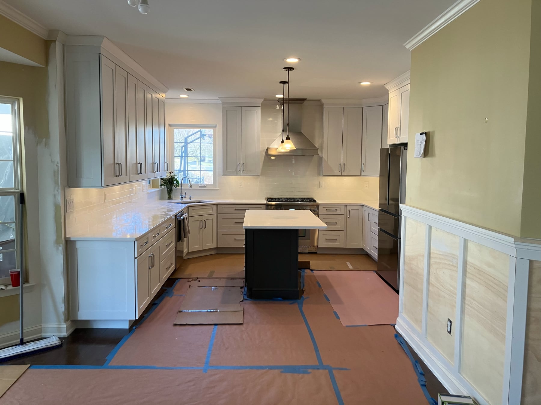 Kitchen after renovation with white cabinetry, stone counters, and a new island