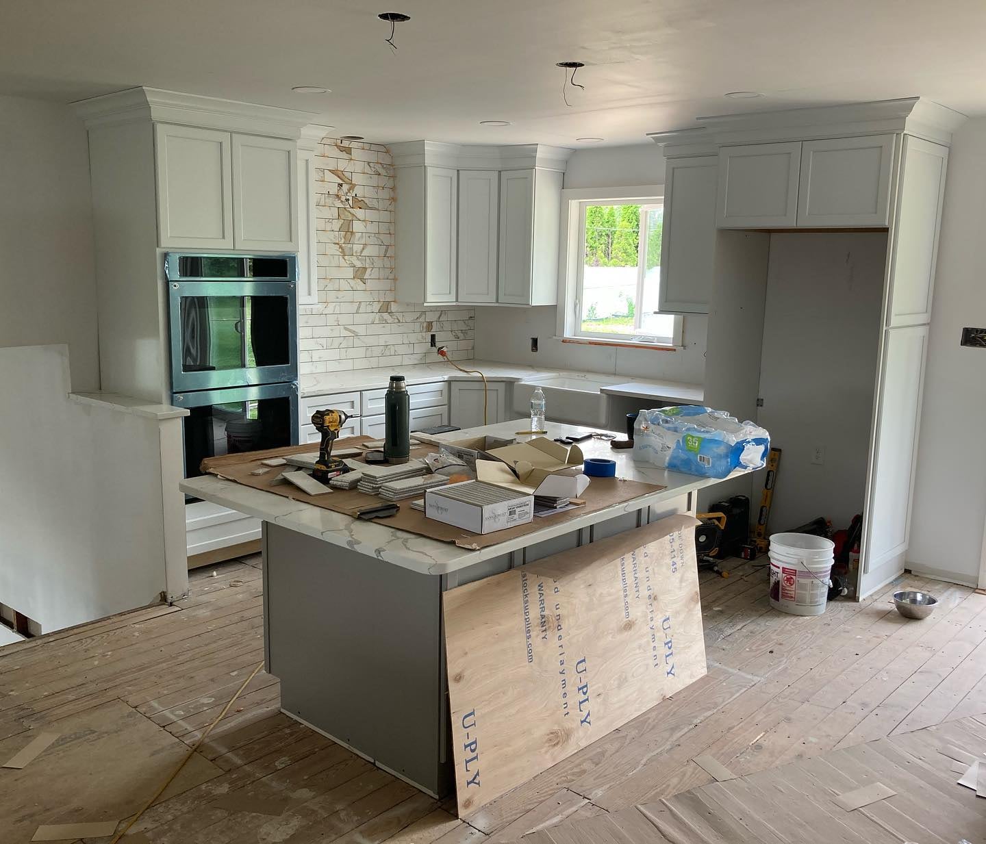 Kitchen after renovation with white cabinetry, marble finishes, and a large island