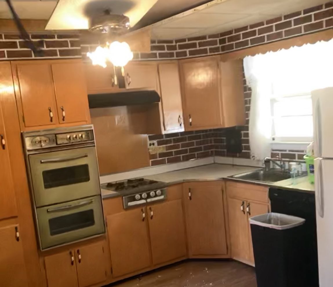 Kitchen before renovation with dated wood cabinetry and appliances